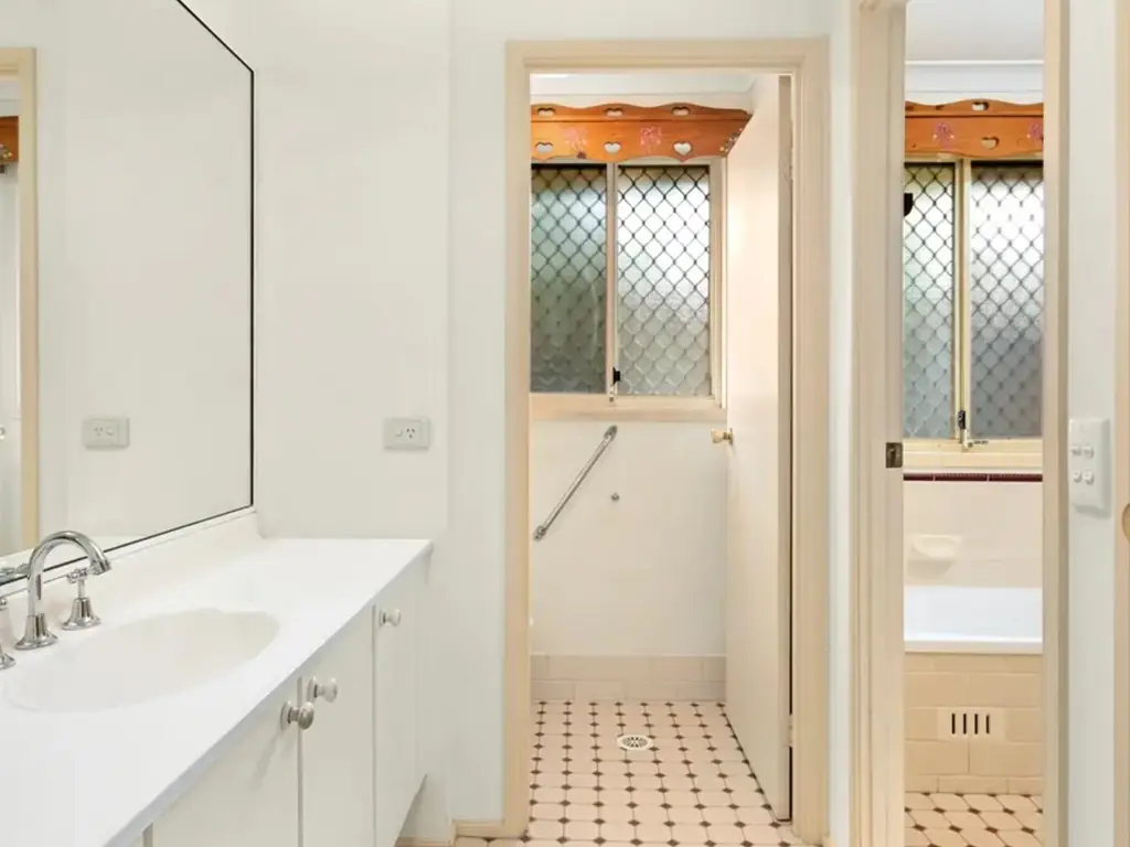 Original 1970s Sydney bathroom before renovation with waist-height wall tiles and a rusted shower screen
