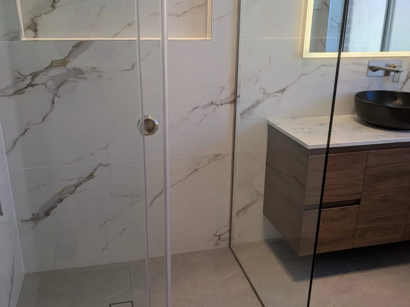 Quakers Hill renovation stone-top vanity and frameless shower glass