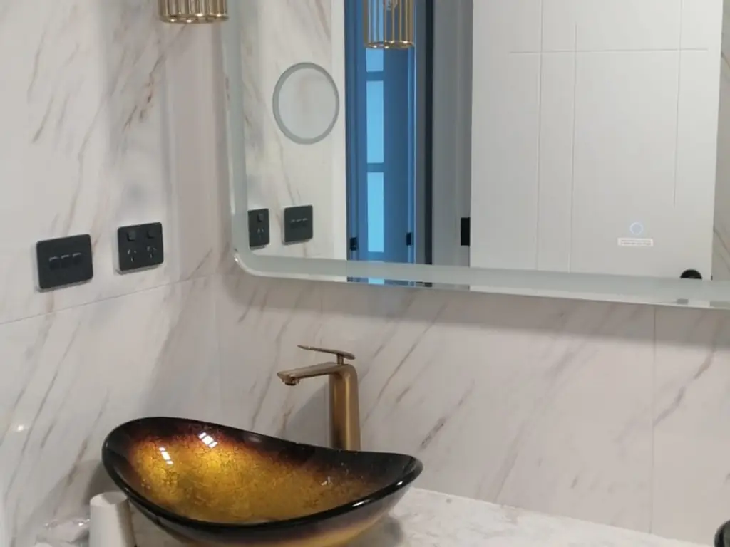 Small bathroom with backlit mirror and clear frameless glass shower screen